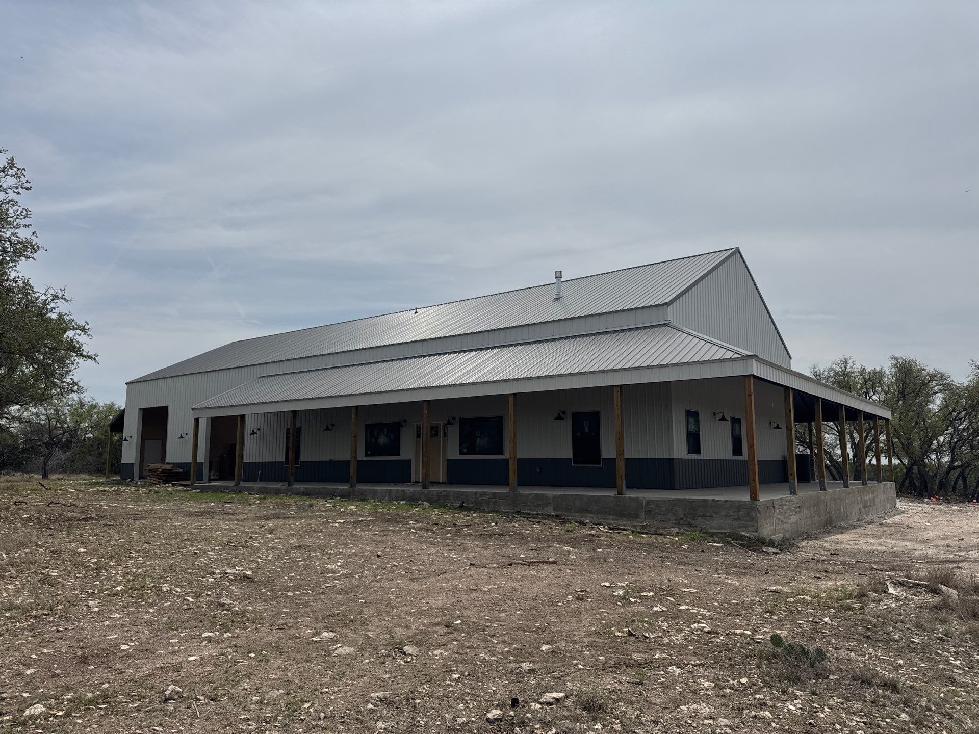 Residential steel building in Helotes, TX, featuring a modern design with a metal roof, porch, and large windows, showcasing strength and style for sustainable construction.